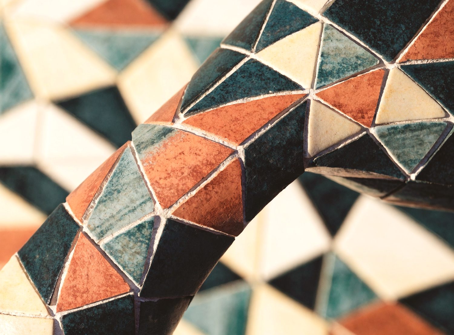 Geometrisches Keramikmosaik in Kupfer-, Patina- und Cremetönen mit feinen Fugen.